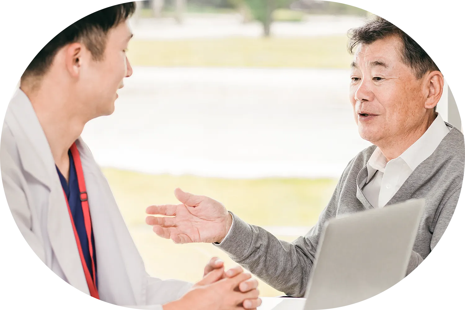 病院で医師と話す高齢男性の写真